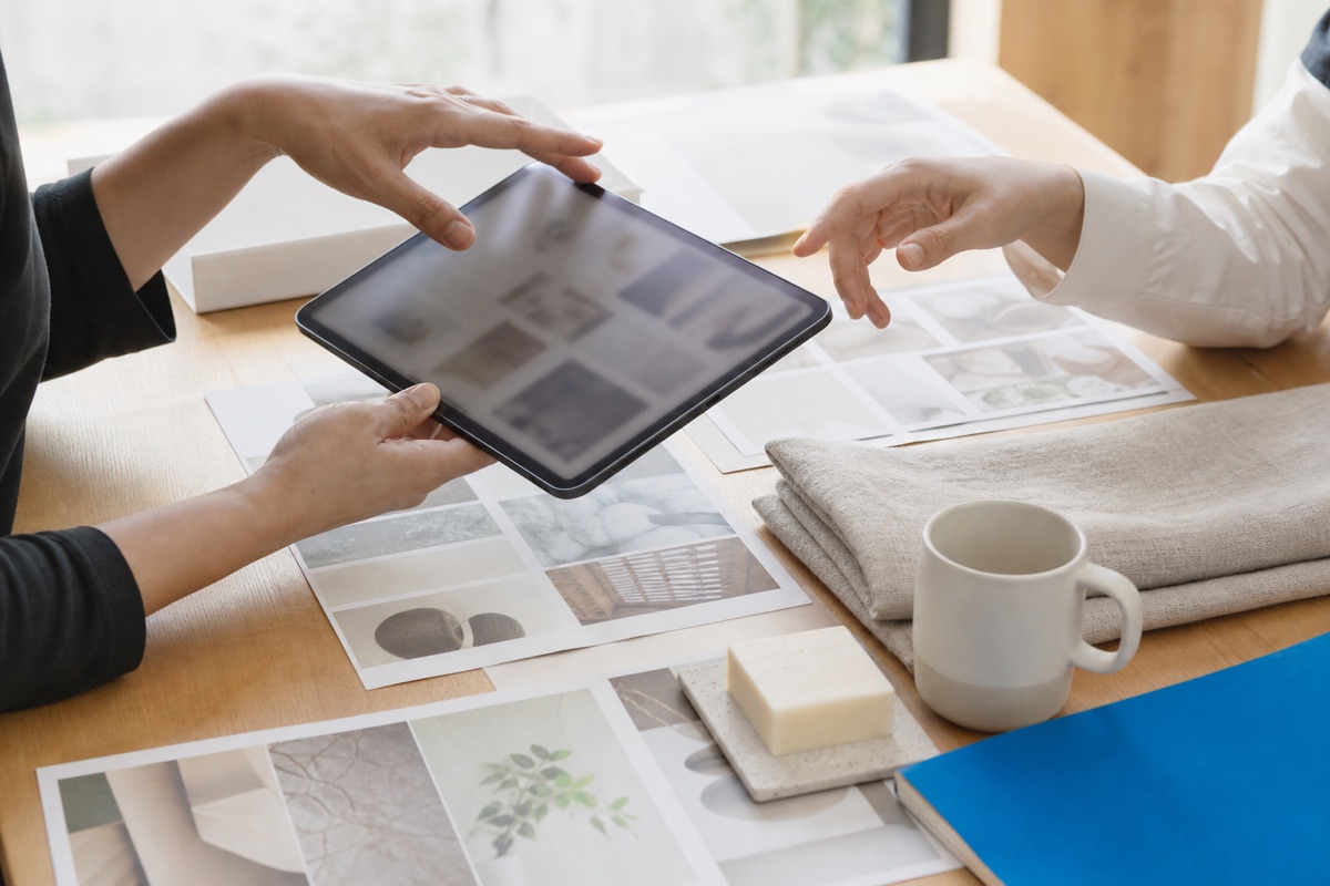 商品サンプルとムードボードを囲んでタブレットで提案を確認する打ち合わせの手元